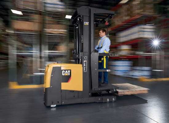 Worker driving Cat High-Level Order Picker through warehouse 